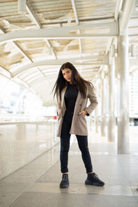 Full length portrait of woman standing in corridor