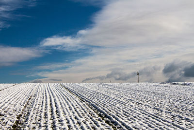 High angle view of snow covered on agricultural field against cloudy sky