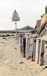 Information sign on beach against sky