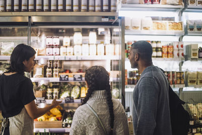 Saleswoman gesturing while talking with customers at store