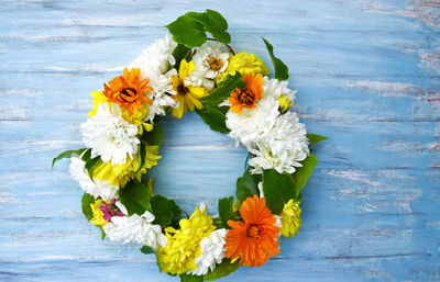 Close-up of autumn flowers wreath selfmade for decoration on blue wood table