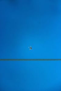 Low angle view of airplane flying against clear blue sky
