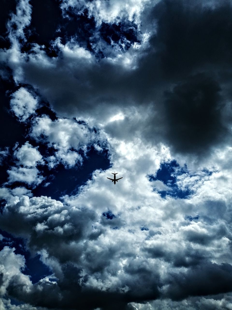 cloud - sky, sky, low angle view, flying, nature, airplane, transportation, air vehicle, mode of transportation, no people, mid-air, beauty in nature, day, outdoors, scenics - nature, overcast, storm, silhouette, motion, plane, directly below