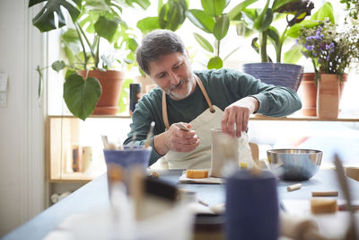 Mature man making craft product in pottery class