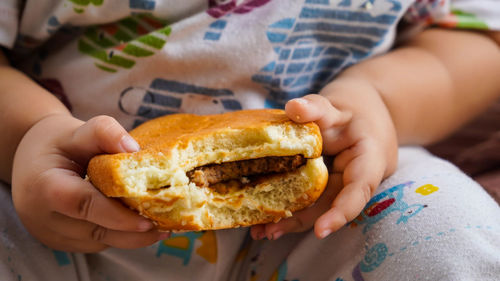 Close-up of baby holding hamburger