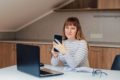 Smiling woman using mobile phone while sitting at office