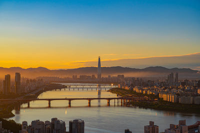 Bridge over river in city during sunset