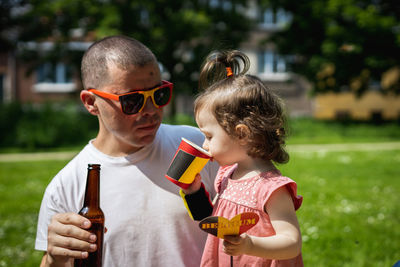 Portrait of dad and daughter drinking drinks and celebrating belgian day.