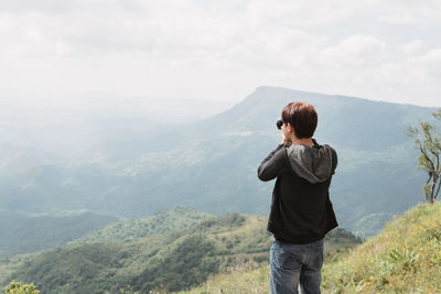 Rear view of man looking at mountains against sky