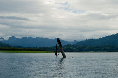 Man with umbrella on lake against sky