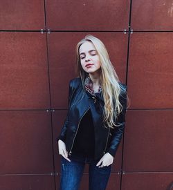 Young woman standing against brick wall