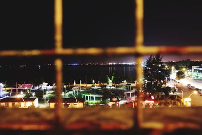Tilt-shift image of illuminated cityscape against sky at night