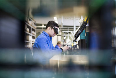 Side view of male technician wearing protective eyewear working in industry