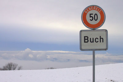 Road sign against sky during winter