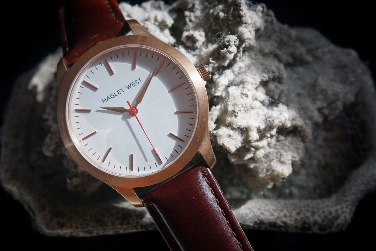 HIGH ANGLE VIEW OF HAND HOLDING CLOCK IN SNOW