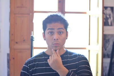 Portrait of young man looking through window