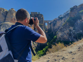 Side view of man photographing against mountain