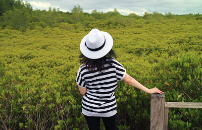 Rear view of woman wearing hat standing on field