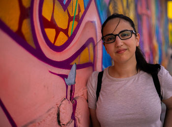 Portrait of young woman standing against wall