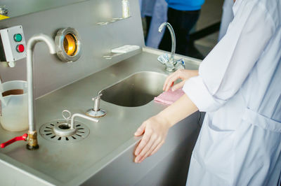 Midsection of doctor standing by machinery in hospital