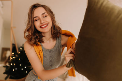 A pretty girl in pajamas rejoices and smiles during the christmas holidays in cozy bedroom interior