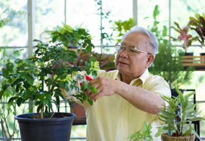 Portrait of man holding eyeglasses by plants