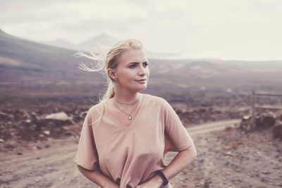 Young woman standing on footpath against mountains