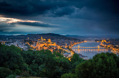 View of illuminated cityscape against cloudy sky