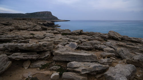 Rock formations on shore against sky