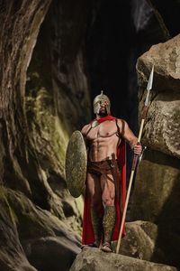 Full length of shirtless man holding rock