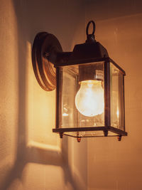 Close-up of illuminated light bulb against wall
