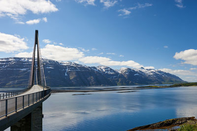 Bridge over river against snowcapped mountains