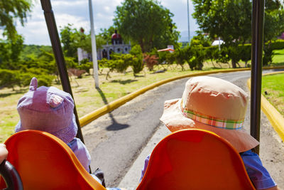 Rear view of children sitting in land vehicle at park