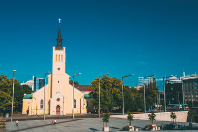 Street amidst buildings against blue sky