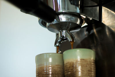 Coffee maker pouring coffee into cups