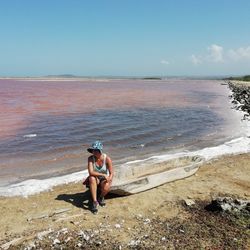 Full length of woman sitting at beach against sky