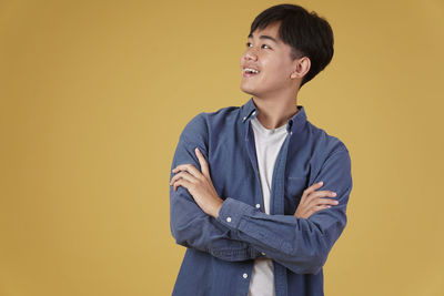 Young man looking away against yellow background