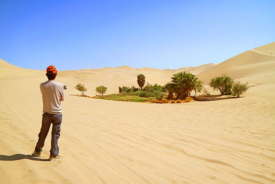 Visitor looking at the small oasis on the vast sand dunes of huacachina desert, ica region, peru