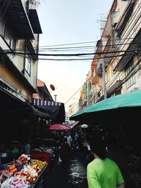 People at market in city against sky