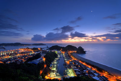 Aerial view of illuminated city against sky at sunset