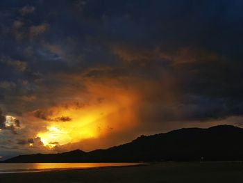 Scenic view of sea against dramatic sky during sunset