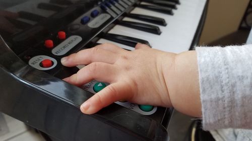 Cropped hands of child playing toy piano