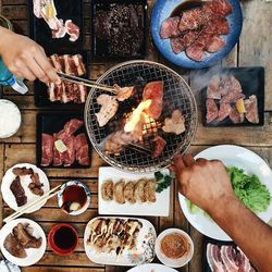 Cropped hands holding barbecuing meat on grill with tongs