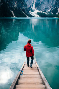 Rear view of man standing on pier over lake