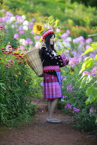 Full length of woman standing by pink flowering plants