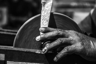 Cropped image of man sharpening knife at workshop