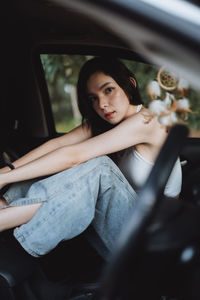 Portrait of young woman sitting in car