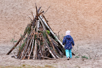 Rear view of girl walking on field by firewood