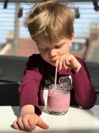 Close-up of boy having drink while sitting at table in cafe