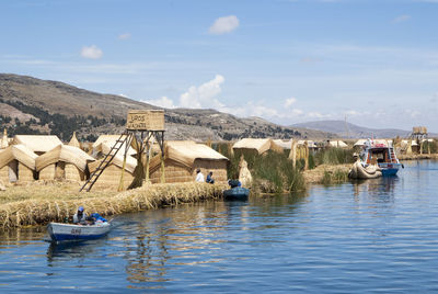 Boats in lake by buildings against sky